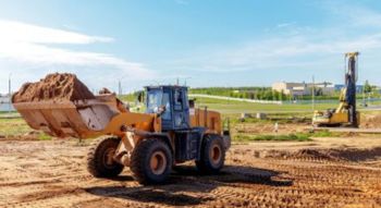 a rural construction with a loader filled with dirt